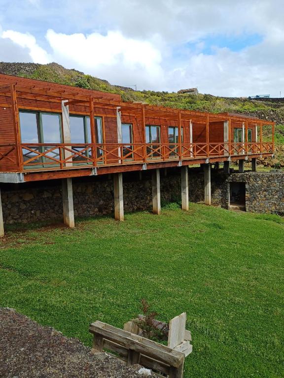 a building with a deck on top of a grass field at Salga Lodge in Angra do Heroísmo