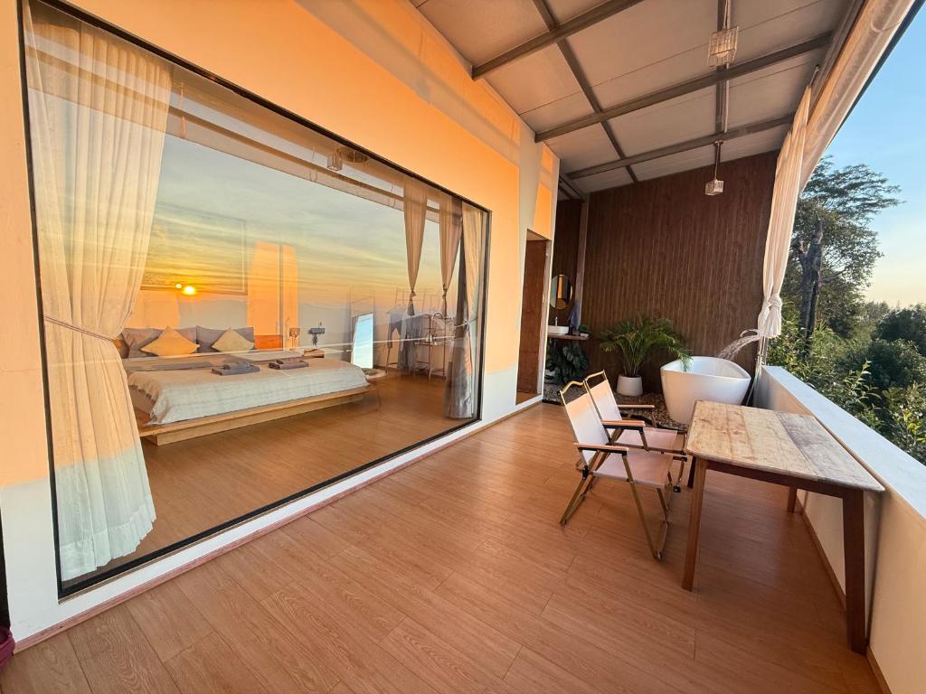 a balcony with a bed and a table and chairs at ไร่ชาอาโซ -ที่พักดอยช้าง in Ban Huai Khai