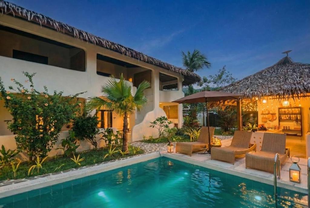 a villa with a swimming pool and a house at Parrots Boutique Resort in San Vicente