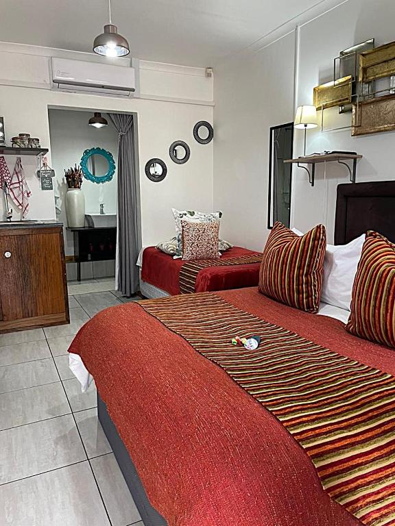 a hotel room with two beds and a mirror at Magalies B&B LANGENHOVENPARK in Universitas