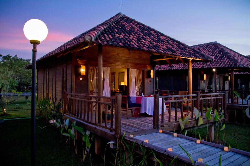 a wooden house with a table on a deck at Gardenia Resort and Spa in Pontianak