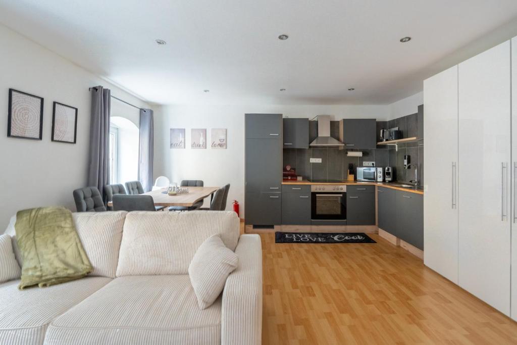a living room with a white couch and a kitchen at Large Maisonette I 90 m2 I For Groups & Families I 9 Guests I 3 Rooms in Kapfenberg
