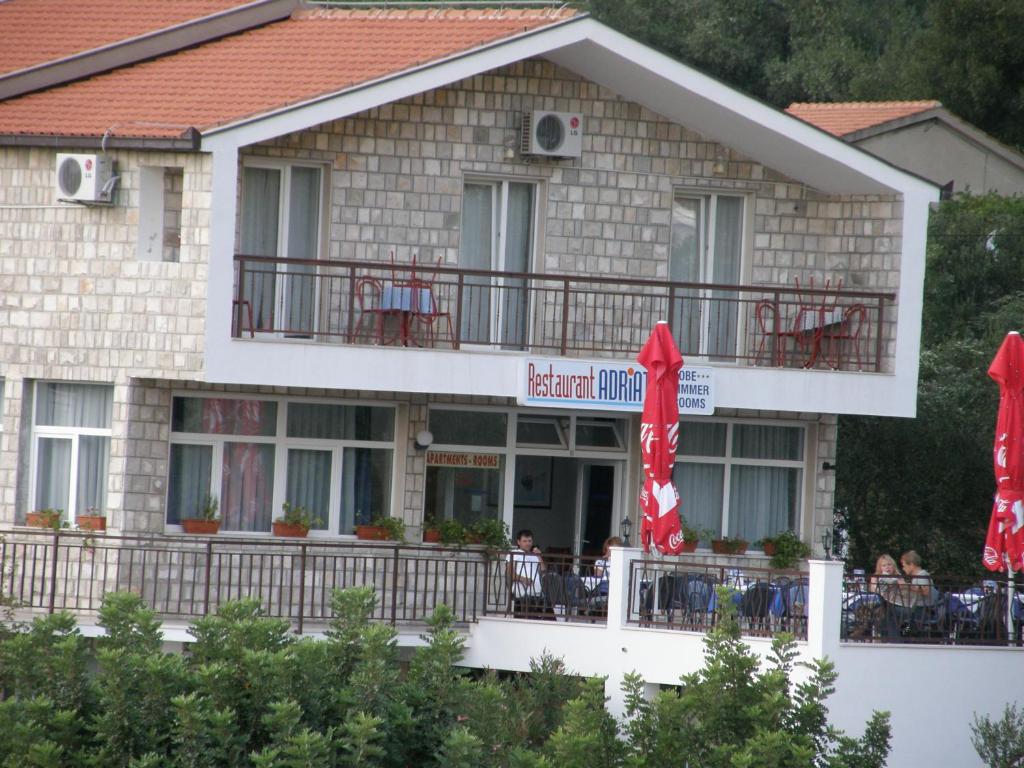 a hotel with red umbrellas in front of a building at Guest House & Restaurant Adriatic Klek in Klek