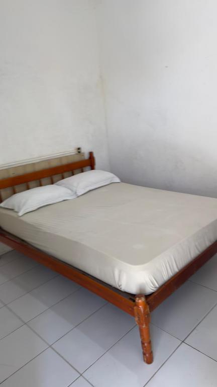 a bed with a wooden frame and white sheets at Quartos Beira Mar ARROIO TEIXEIRA in Capão da Canoa