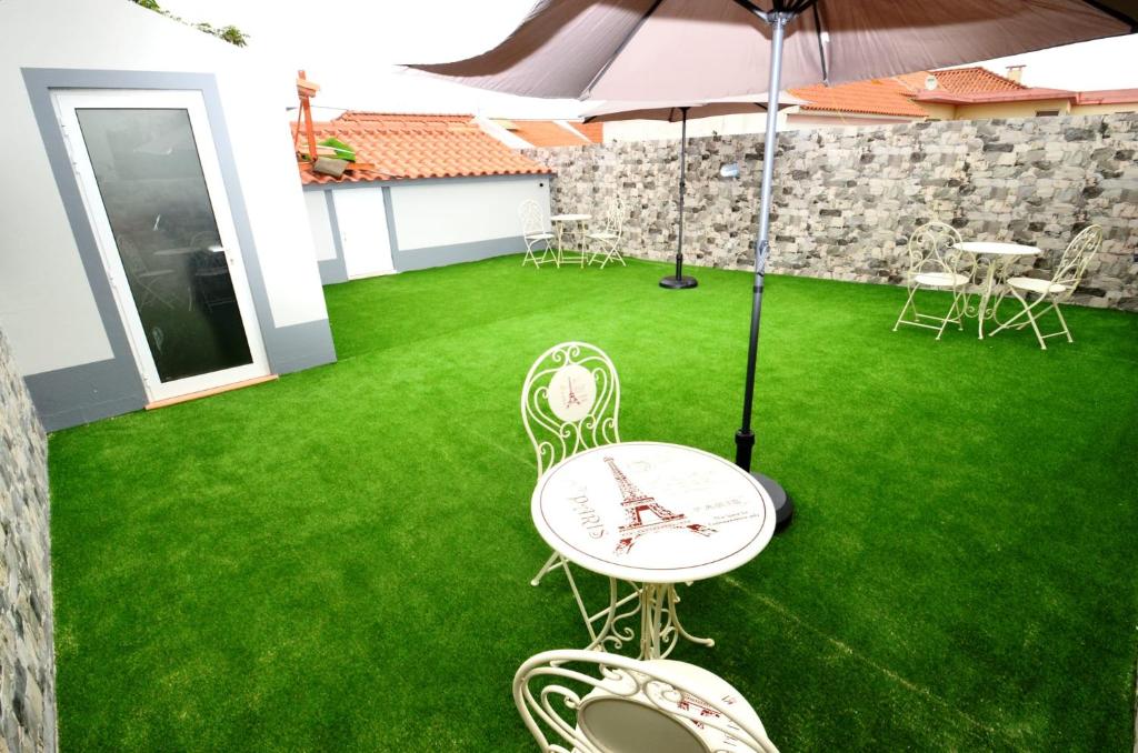 a patio with a table and chairs and an umbrella at O Cantinho Guesthouse com Terraço e Vistas em Quinta do Anjo in Quinta do Anjo