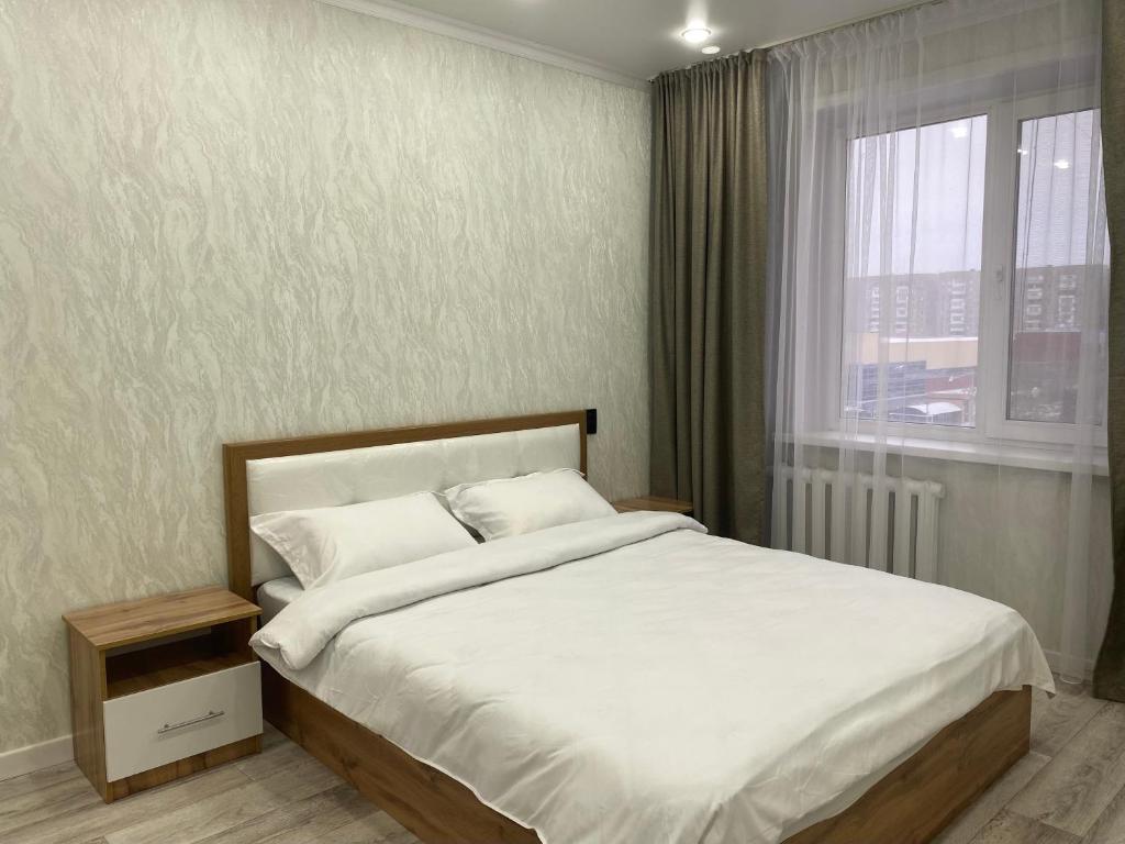 a bedroom with a large bed with a window at Elegant Home Stepnoy in Karagandy