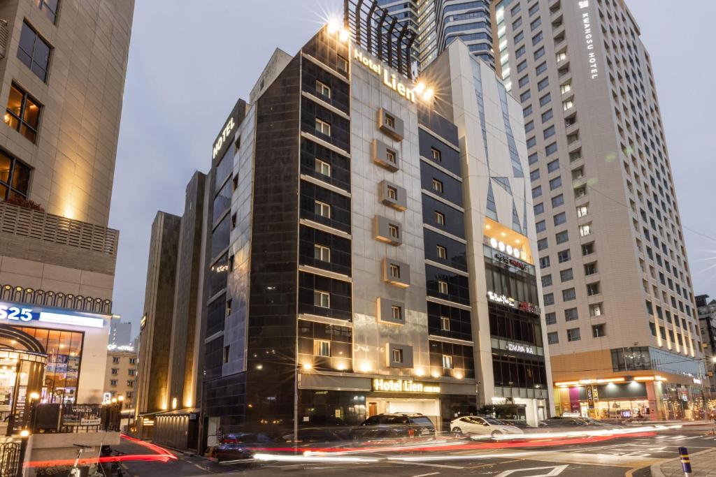a tall building on a city street with buildings at Lien Hotel Haeundae in Busan