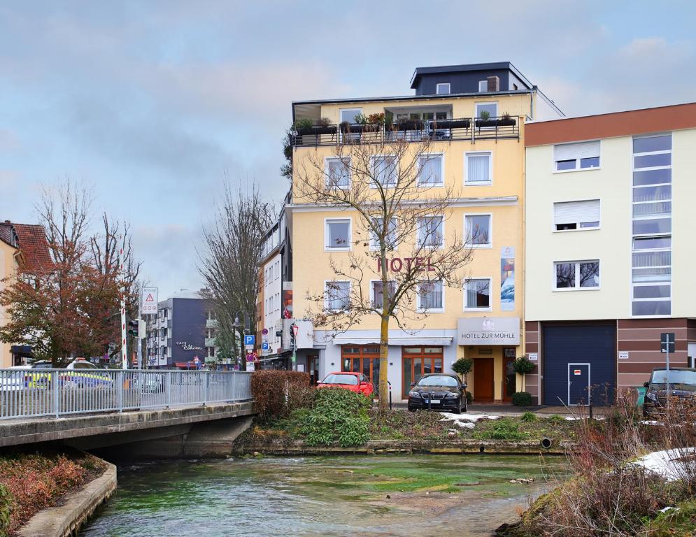a river in front of a building with a bridge at Hotel zur Mühle in Paderborn