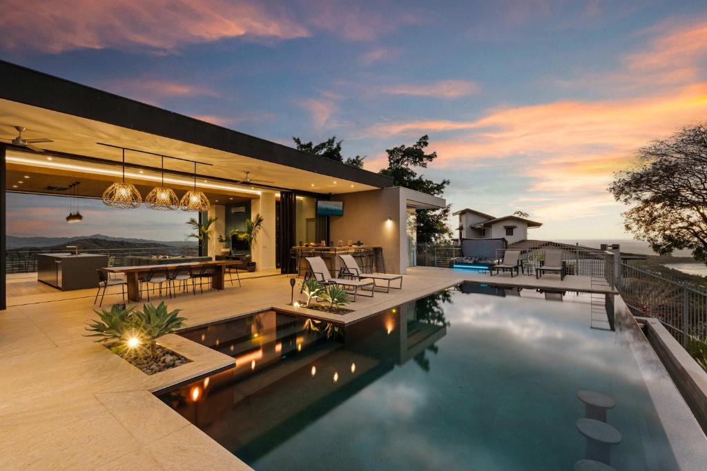 a house with a swimming pool and a dining area at Infinity Pool Villa , 4 Suites & Private Casita in Tamarindo