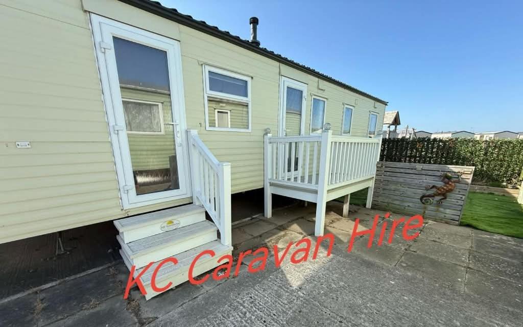 a house with a porch and stairs in front of it at KC Caravan Hire in Kinmel Bay