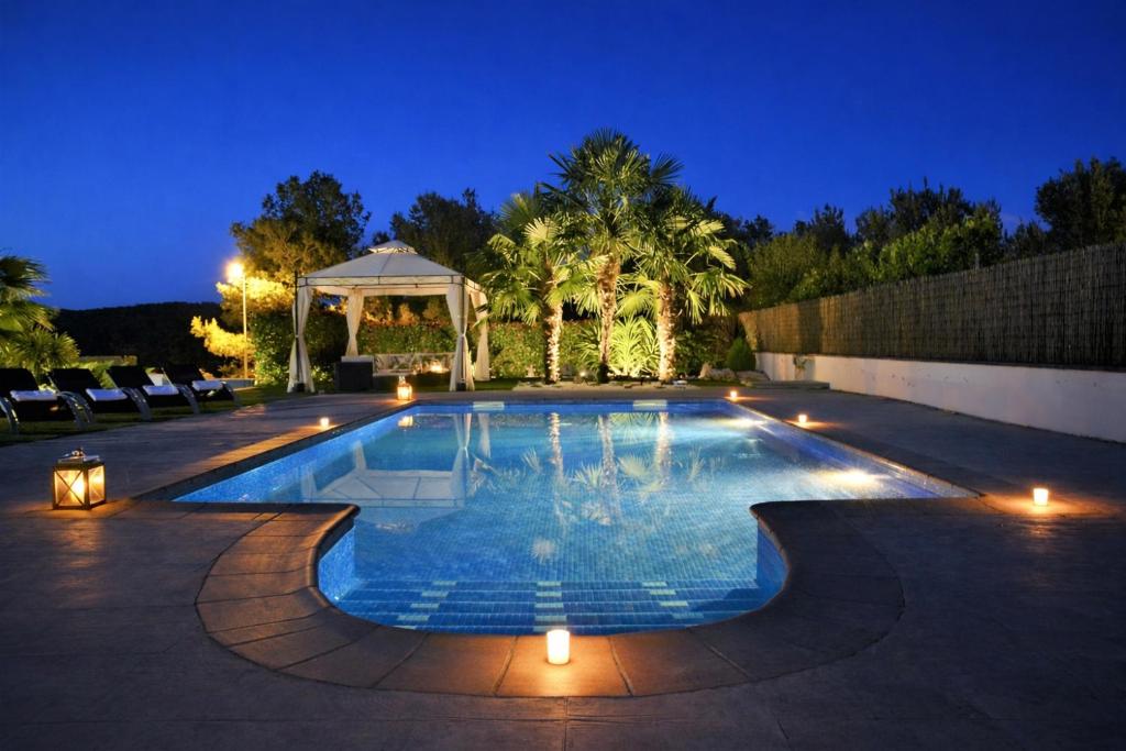 a swimming pool with lights in a backyard at night at Villa Sitges La Calma 10 minutes drive Sitges 2 minutes walk Garraf Park AC in Sant Pere de Ribes