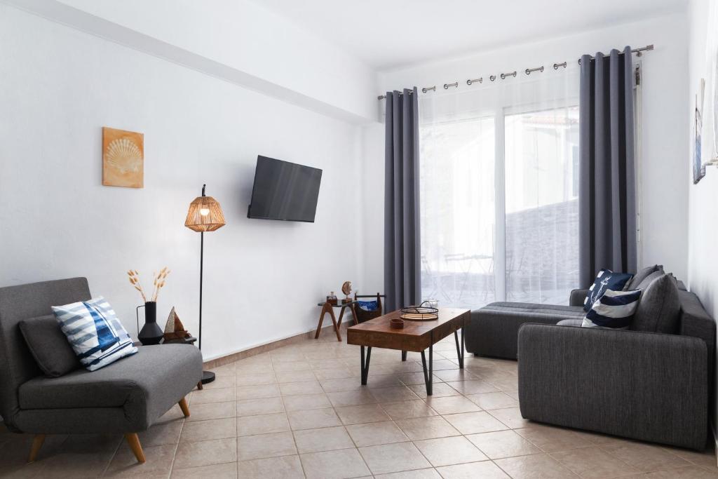 a living room with two couches and a tv at Andros Apartments with Free Parking in Steniaí