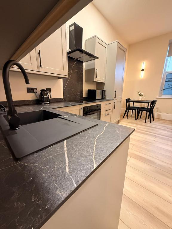 a kitchen with a black counter top and a sink at Rambler's Rest Boutique Apartment in Westward Ho