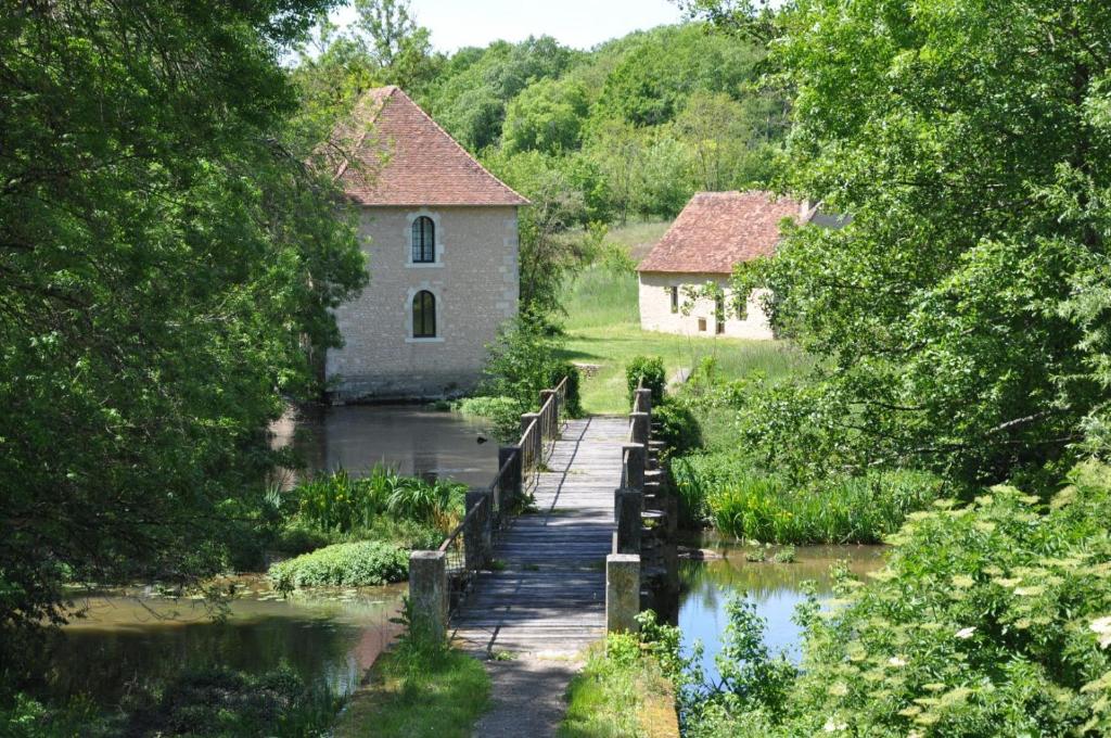 a wooden bridge over a river with two buildings at Le moulin brûlé in Béthines
