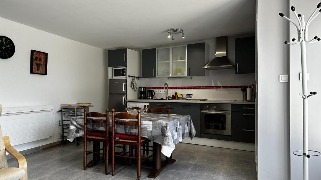 a kitchen with black cabinets and a table with chairs at Gîte des voines in Maillé