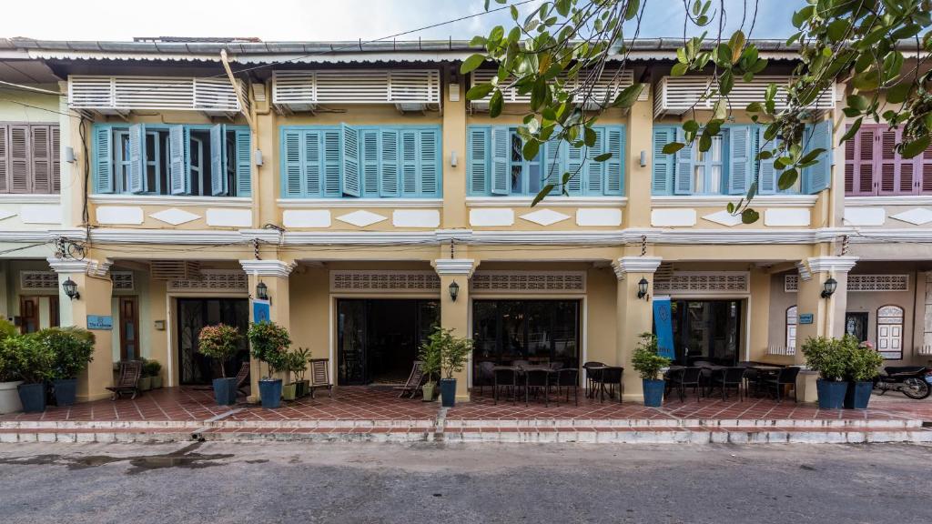 a large yellow building with blue shuttered windows at The Columns in Kampot