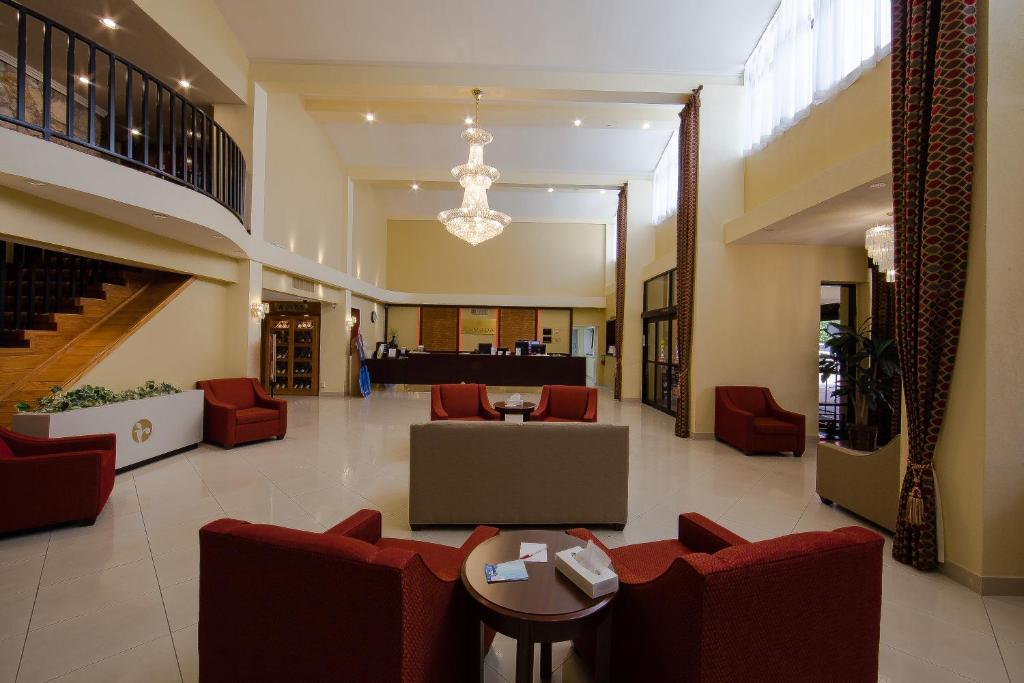 a lobby of a hospital with red chairs and tables at Ramada by Wyndham Houston Intercontinental Airport East in Humble