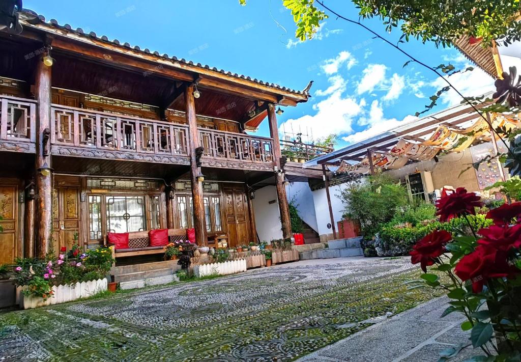 an old house with a porch and flowers in front at In Spring Country Courtyard in Lijiang in Lijiang