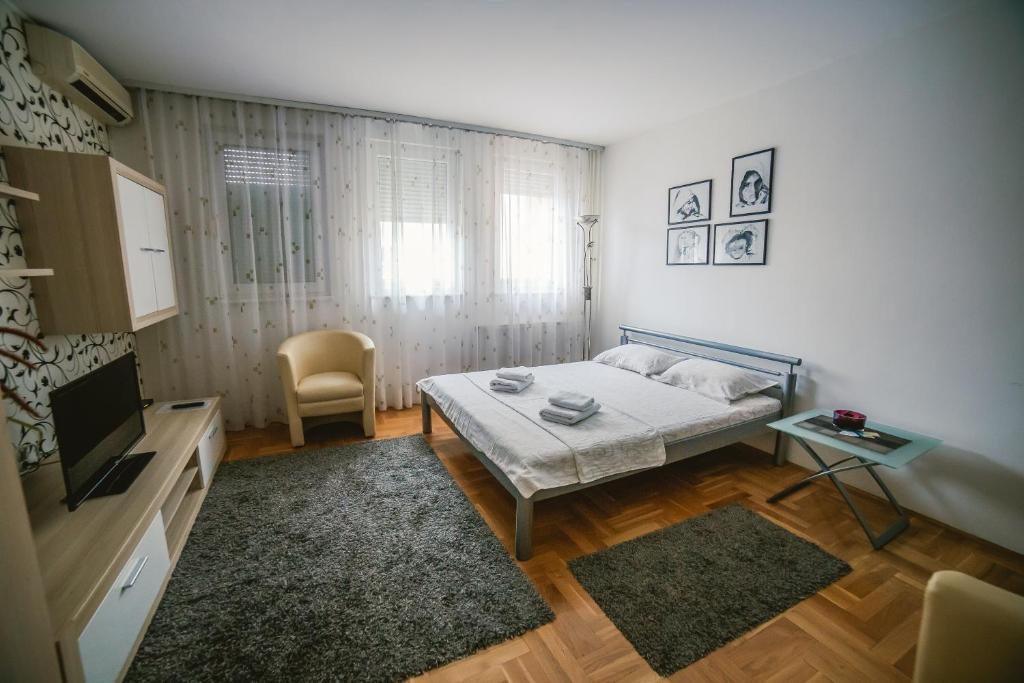 um pequeno quarto com uma cama e uma televisão em Apartment Stela em Belgrado