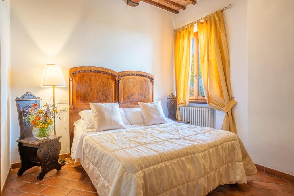 a bedroom with a large bed with a wooden headboard at La Corte Medicea in Montepulciano