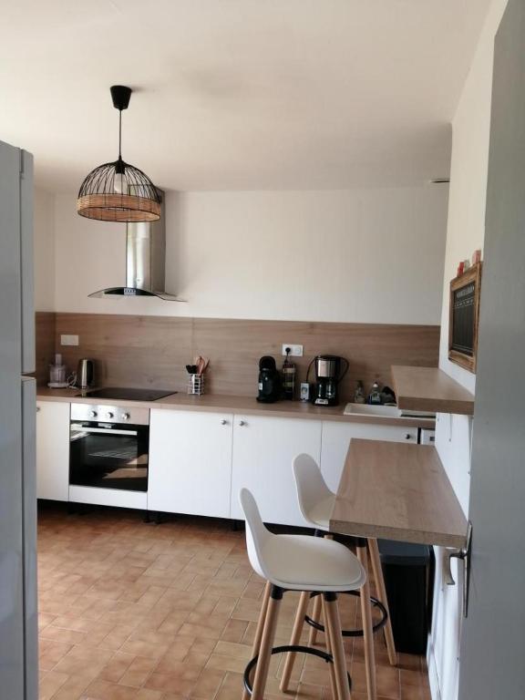 a kitchen with white cabinets and a table with chairs at Le clos des vaches in Usson-du-Poitou