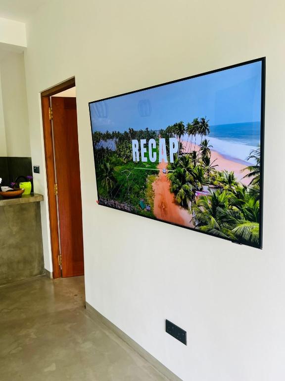 a flat screen tv on a wall in a living room at Mama Place in Hikkaduwa