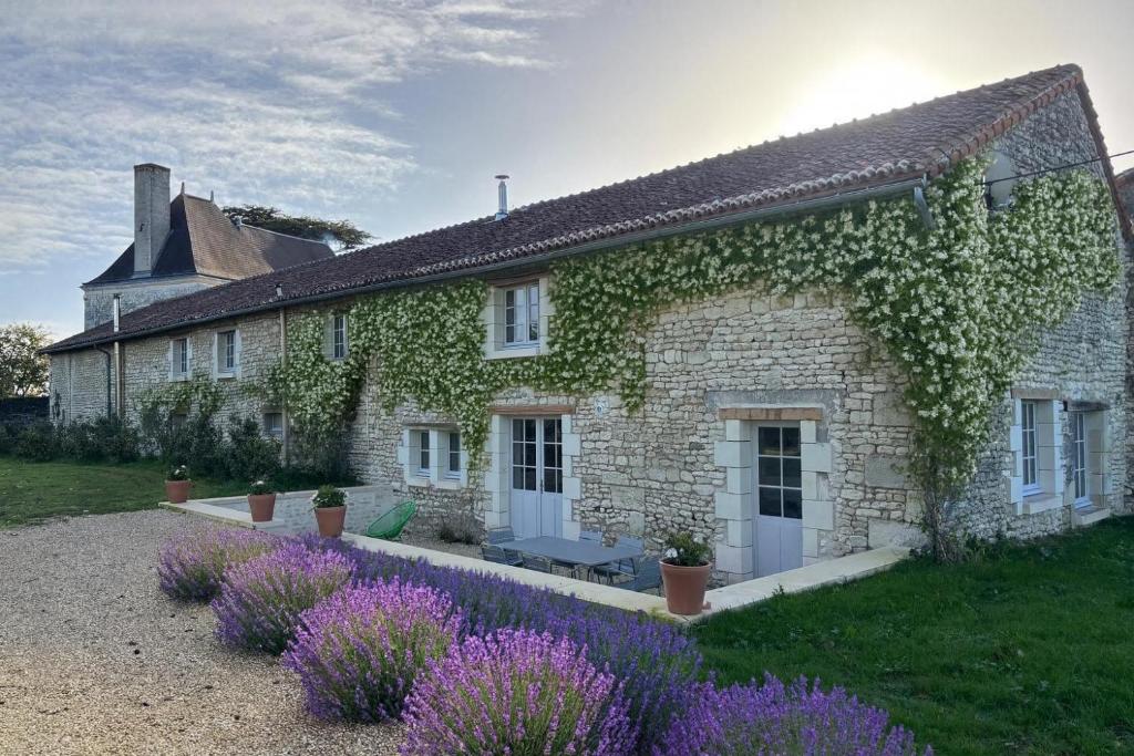 an ivy covered house with purple flowers in front of it at Gîte de la petite touche in Seligny