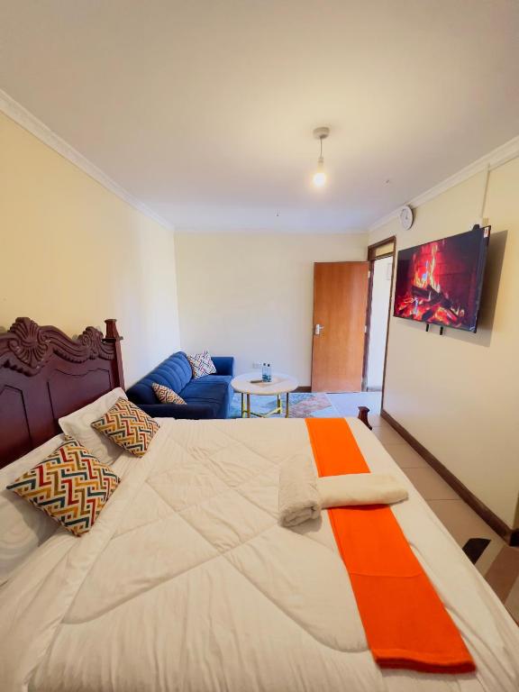 a bedroom with a large bed and a couch at GREENFIELD STUDlO DONHOLM in Nairobi