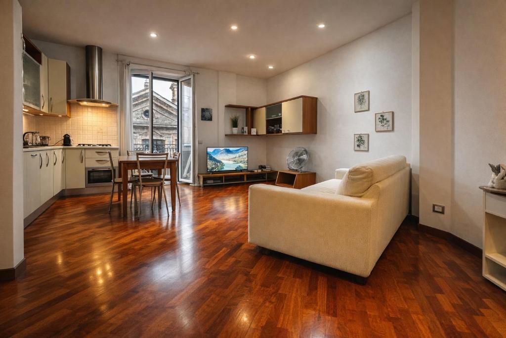 a living room with a white couch and a kitchen at Suite Mazzini in Ravenna