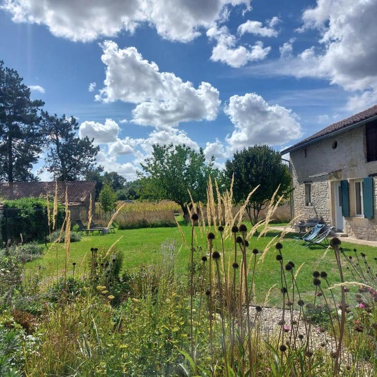 a garden with tall grass and flowers in front of a building at Émeraude in Voulême