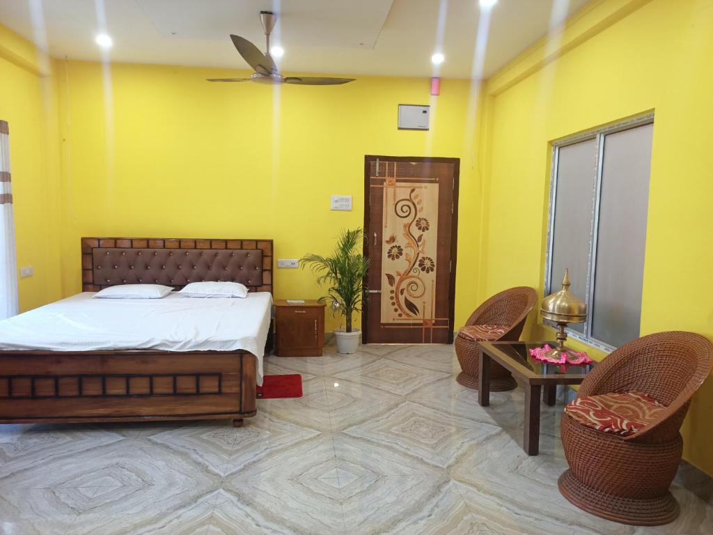 a bedroom with a bed and two chairs at DENEVA Inn in Nowgong