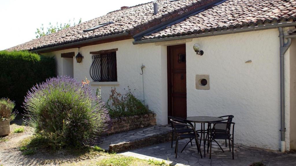 a table and chairs in front of a white house at La boulitte in Asnois