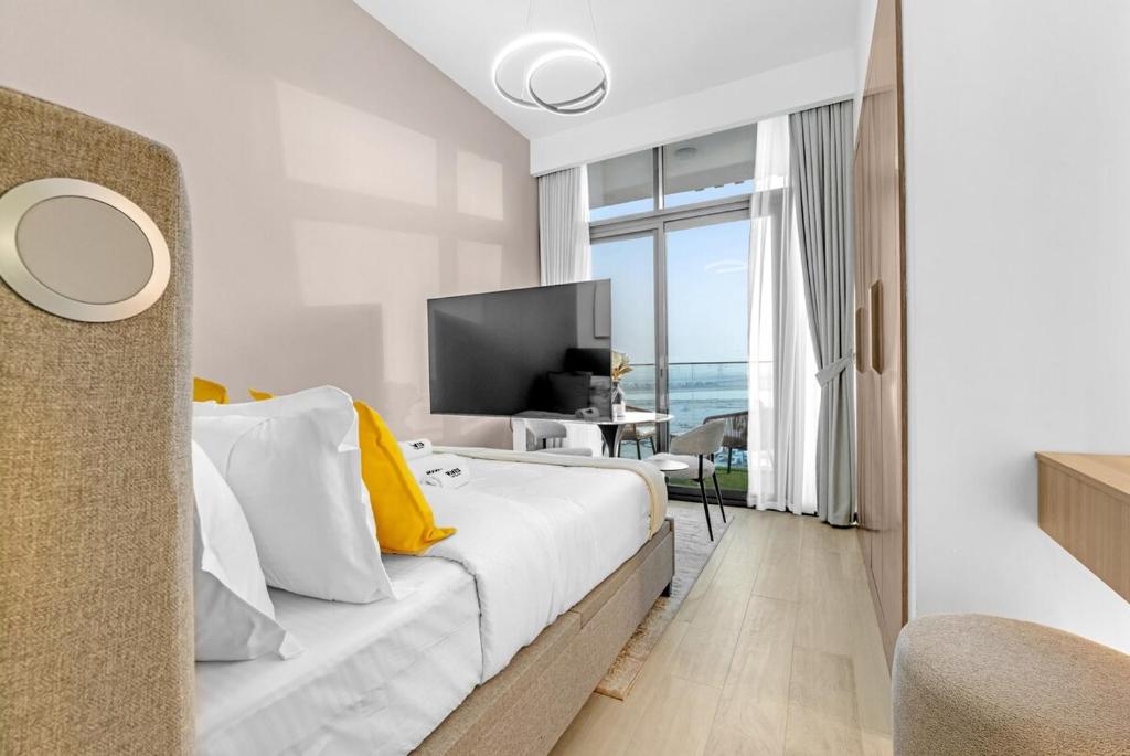 a white bedroom with a large bed with yellow pillows at Waves - Modern & Vibrant Studio With Skyline View in Sabkhah