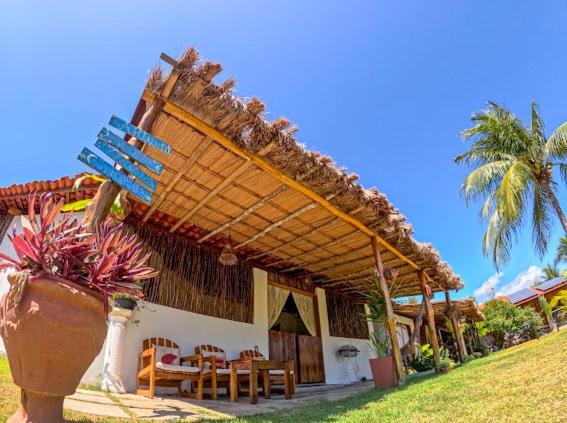 a building with a wooden roof with a table and chairs at Casa do Francês in Japaratinga
