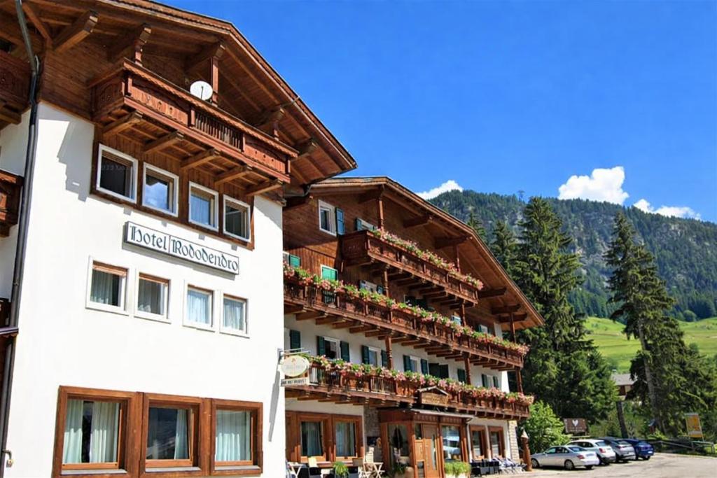 a hotel in the mountains with flowers on the balconies at Hotel Rododendro Val di Fassa in Campitello di Fassa