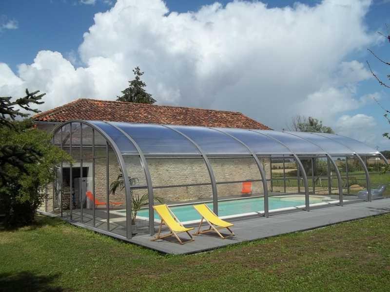 a greenhouse with two yellow chairs and a swimming pool at Le ry de pouzioux in Chauvigny