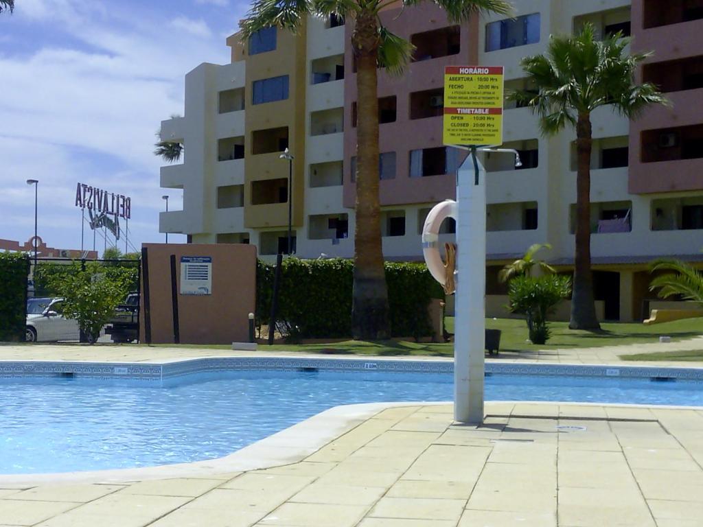 ein Schwimmbad mit einem Schild neben einem Gebäude in der Unterkunft Bellavista Mar in Albufeira