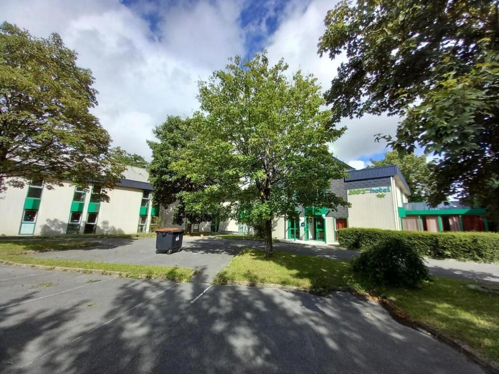a building with a tree in the middle of a street at Mot Hotel in Claye-Souilly