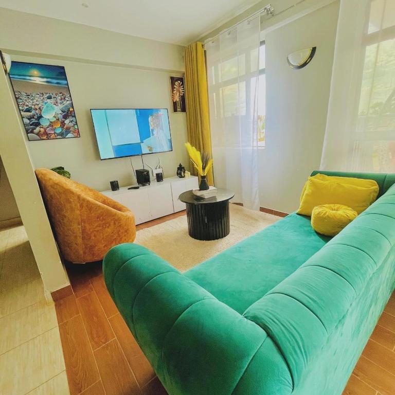 a living room with a green couch and a television at Bethany Cushy Home Ltd in Kisii