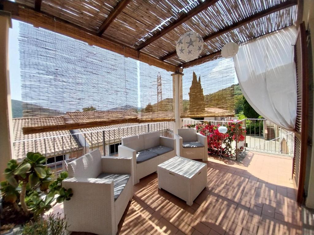 a patio with white furniture and a large window at La casa accanto in Rio nellʼElba