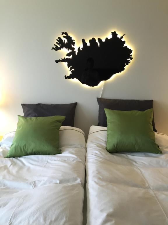 a bedroom with two beds with white sheets and green pillows at Sea View Apartment in Keflavík