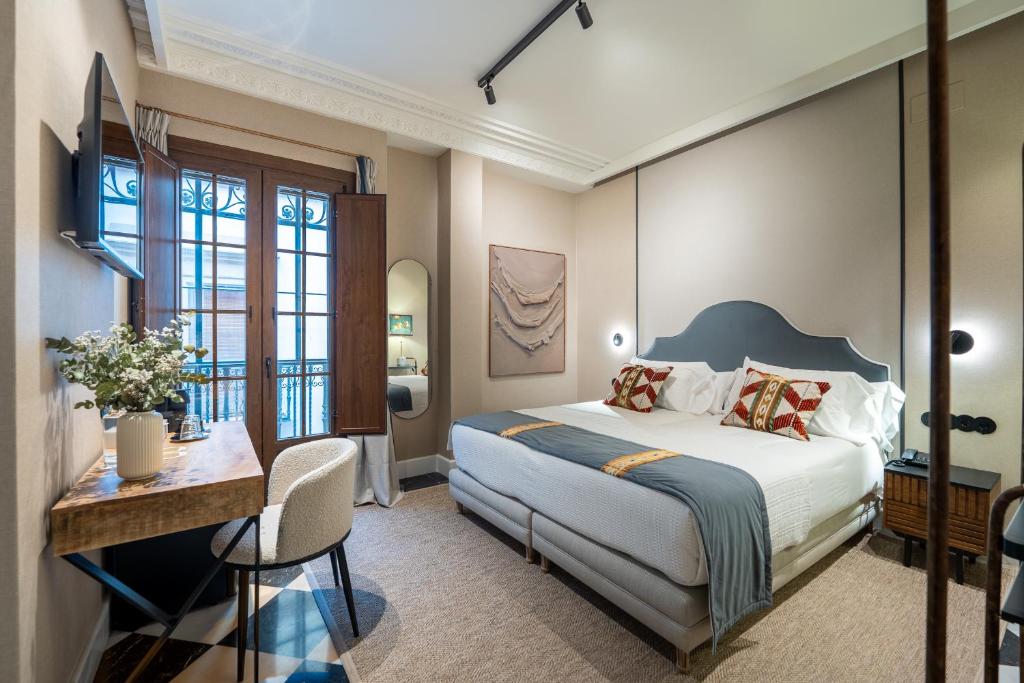 a hotel room with a bed and a desk and a table at De Domínguez Hotel Boutique in Seville