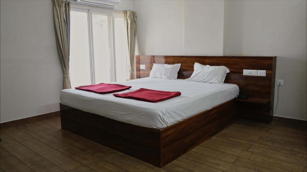 a bedroom with a bed with two red towels on it at Rams Inn in Krishnagiri