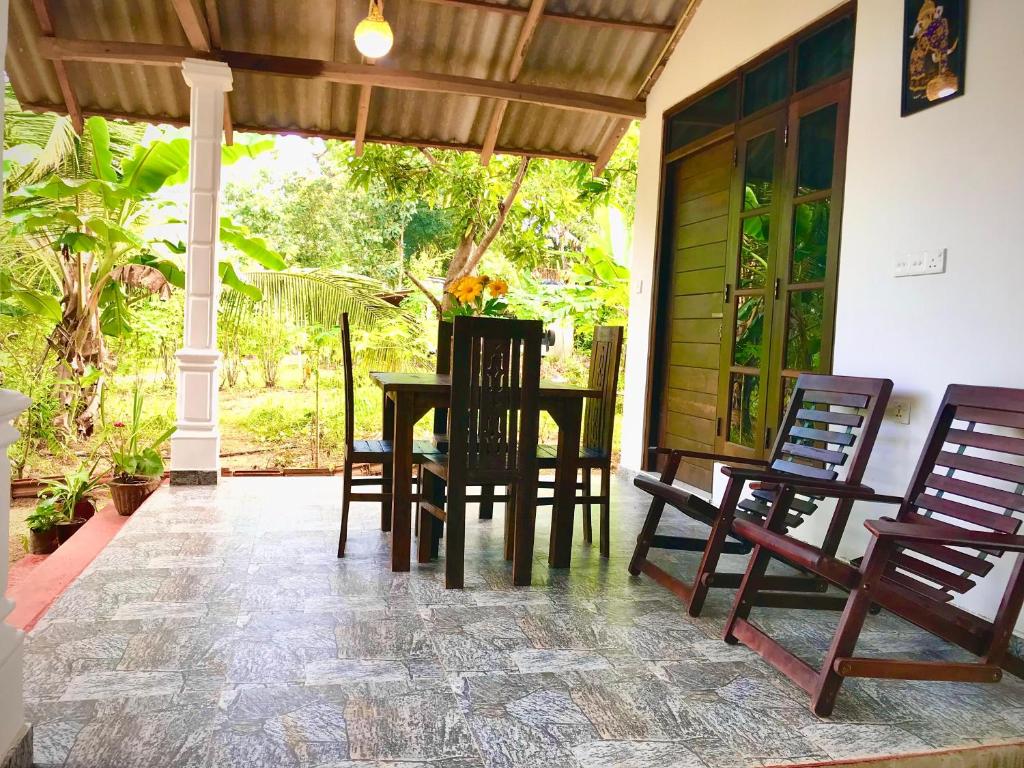 a dining room with a table and chairs on a porch at Diyana Cottage in Sigiriya