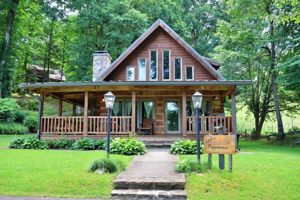 a large wooden cabin with a porch in a park at The Meadows in Cherokee