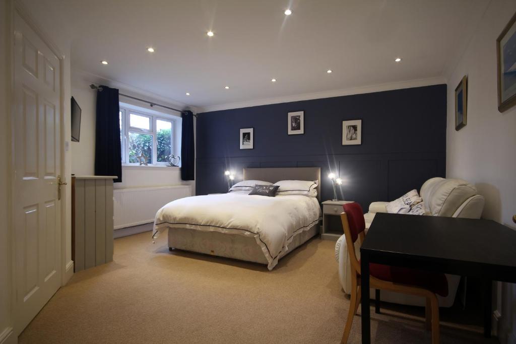 a bedroom with two beds and a desk and a window at Mahe - Lee on the Solent in Lee-on-the-Solent