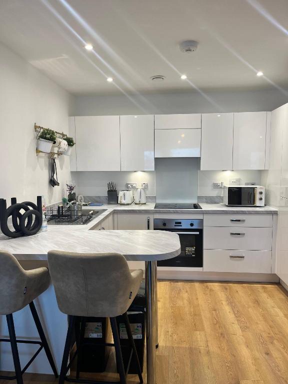 a kitchen with white cabinets and a table and chairs at Prime Location - Apt - Stay 4 - Lakeside - Parking in Grays Thurrock