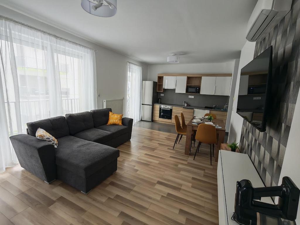 a living room with a couch and a kitchen at Juniper 3 Business in Kecskemét