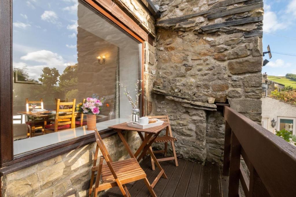 a balcony with a table and chairs on a stone wall at 2 Bed in Settle oc-ds1038 in Settle