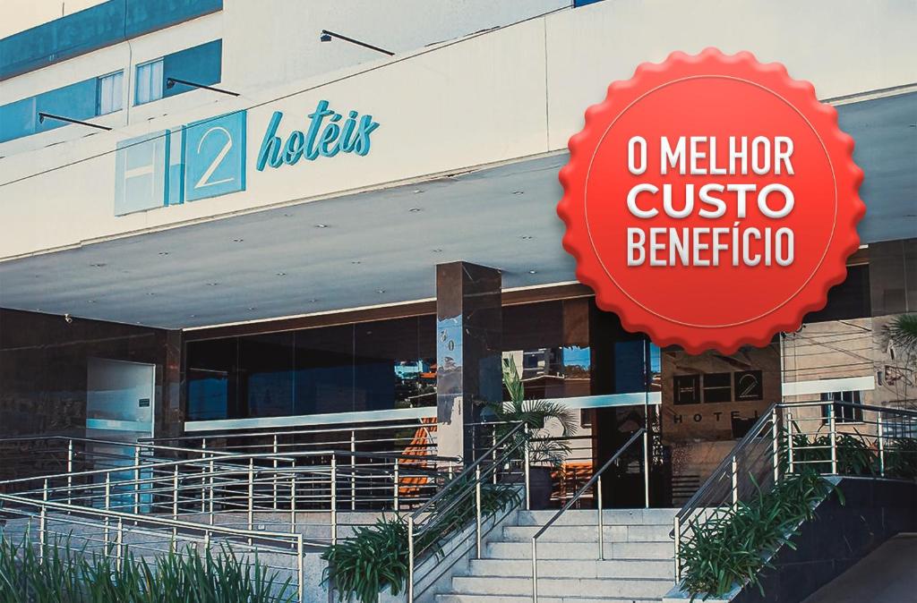 a building with a sign in front of a store at Hotel H2 Congonhas in Congonhas